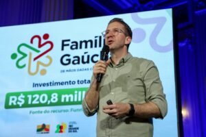 Secretário Beto Fantinel está com o microfone na mão em frente a uma painel com dados do Programa Família Gaúcha