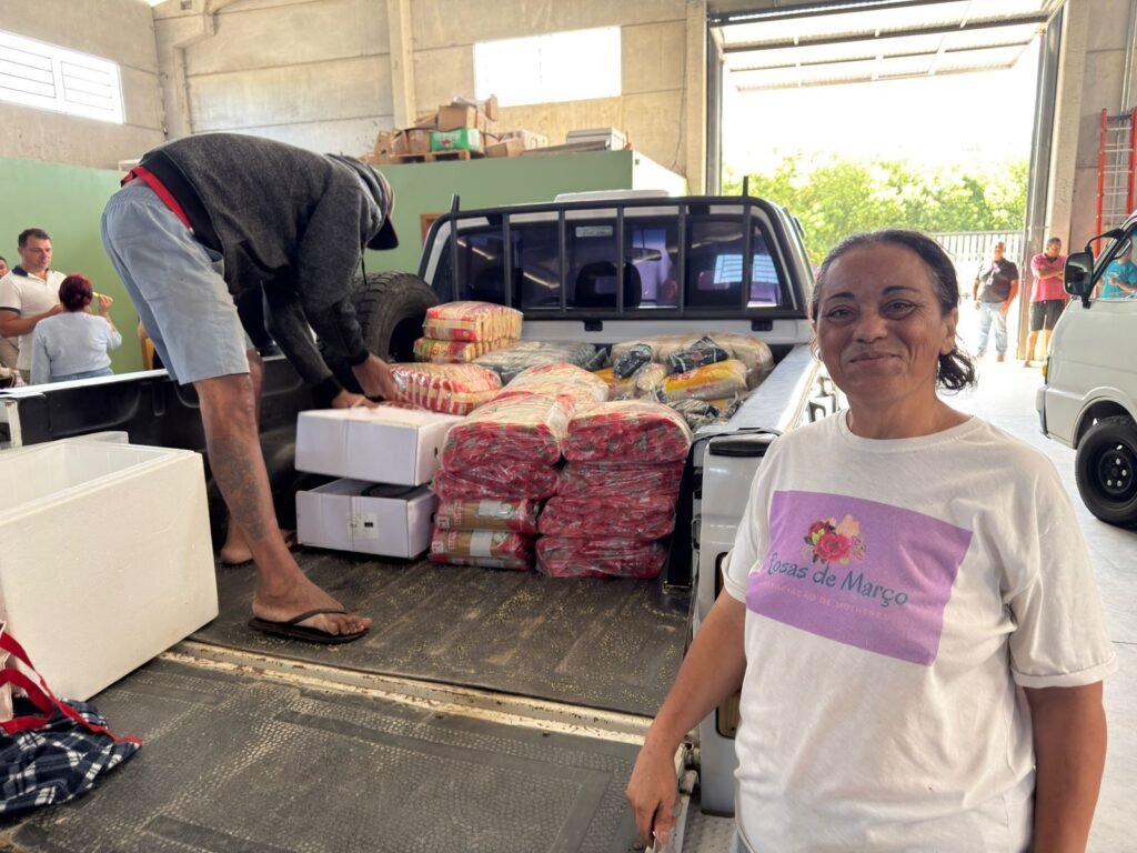 Cozinheira que recebe alimentos aparece na frente de um veículo com os itens